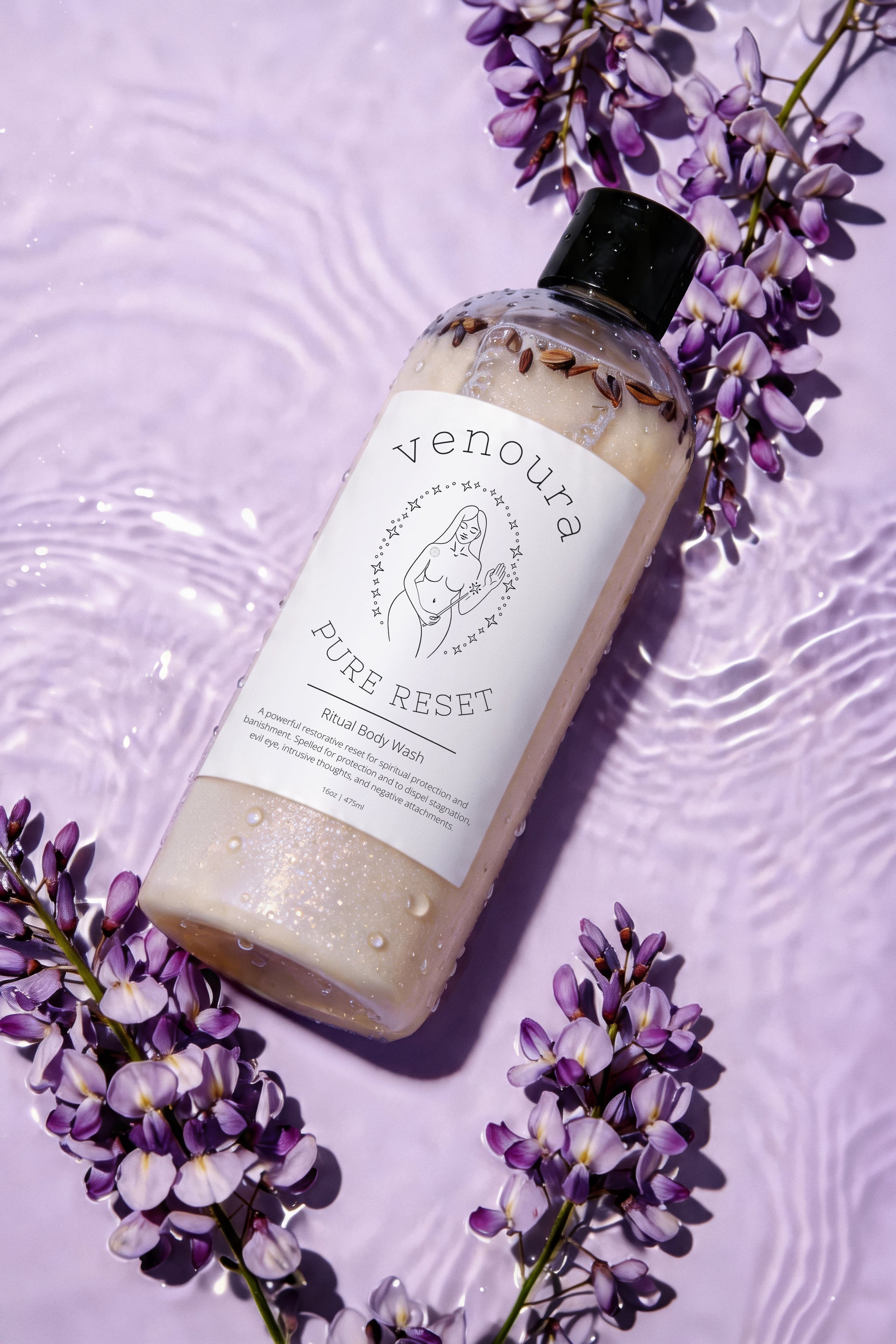 Venoura Pure Reset Mineral Body Wash in a clear bottle with a black cap, styled on a lavender background with purple wisteria flowers.