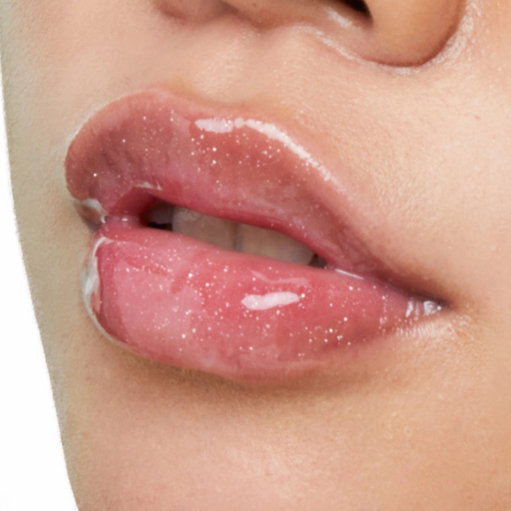 Close-up of glossy pink lips with fine glitter, showing a shimmering lip product on a person's face.