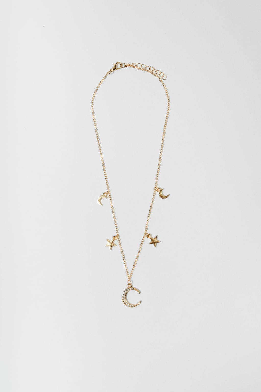 A delicate gold chain necklace featuring multiple small celestial charms, including crescent moons and stars, displayed against a clean, light gray background.