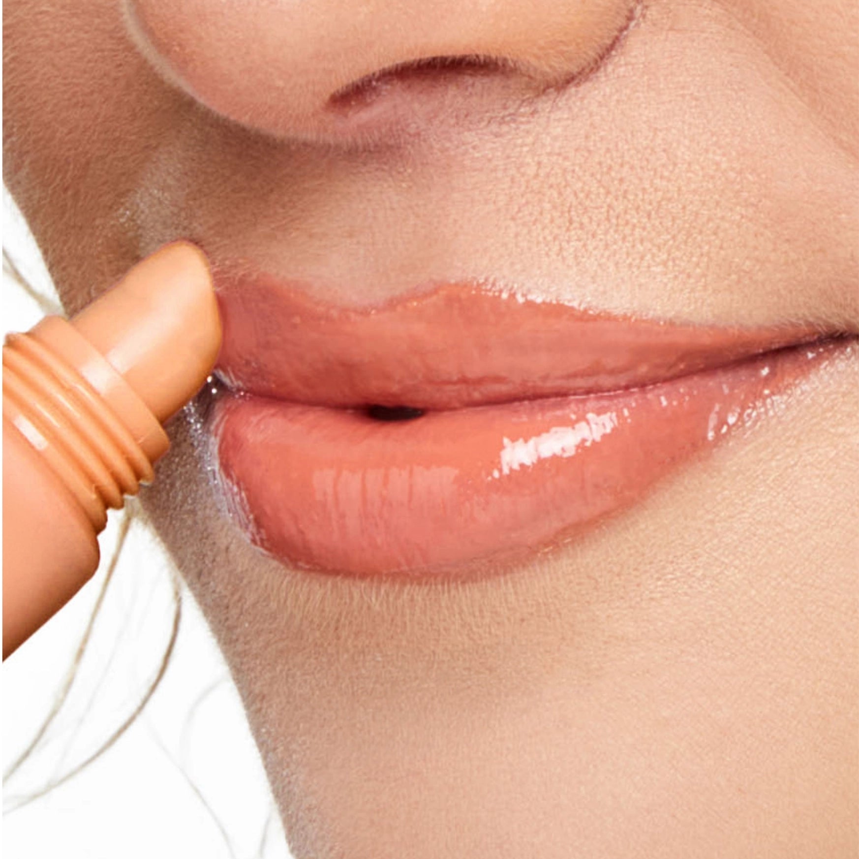 Close-up of a person applying lip gloss to their lips.