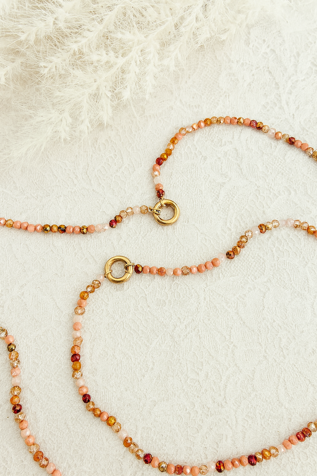Necklace with beaded chain and gold clasp on a textured white surface