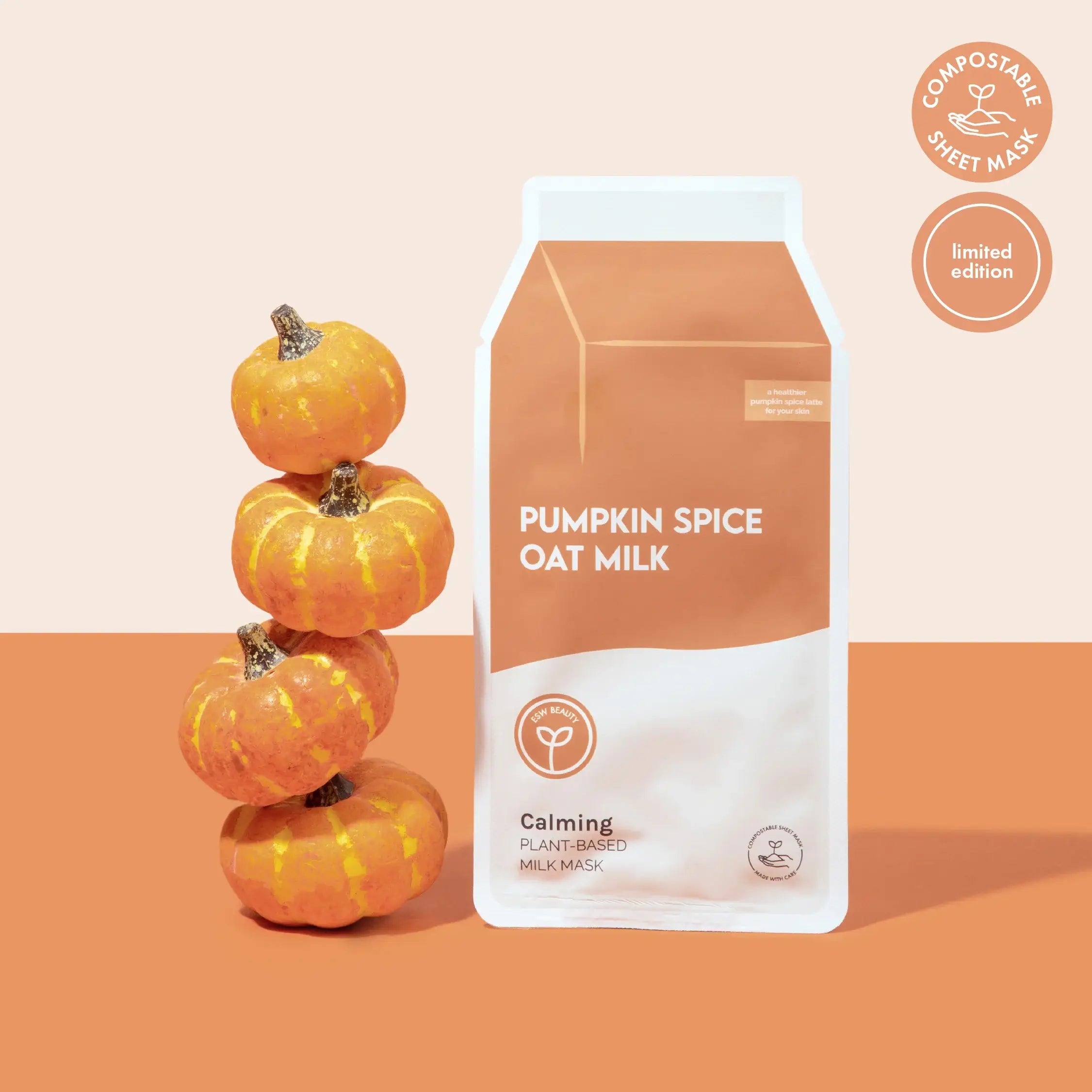 Packaging of pumpkin spice oat milk with decorative pumpkins on a two-tone background