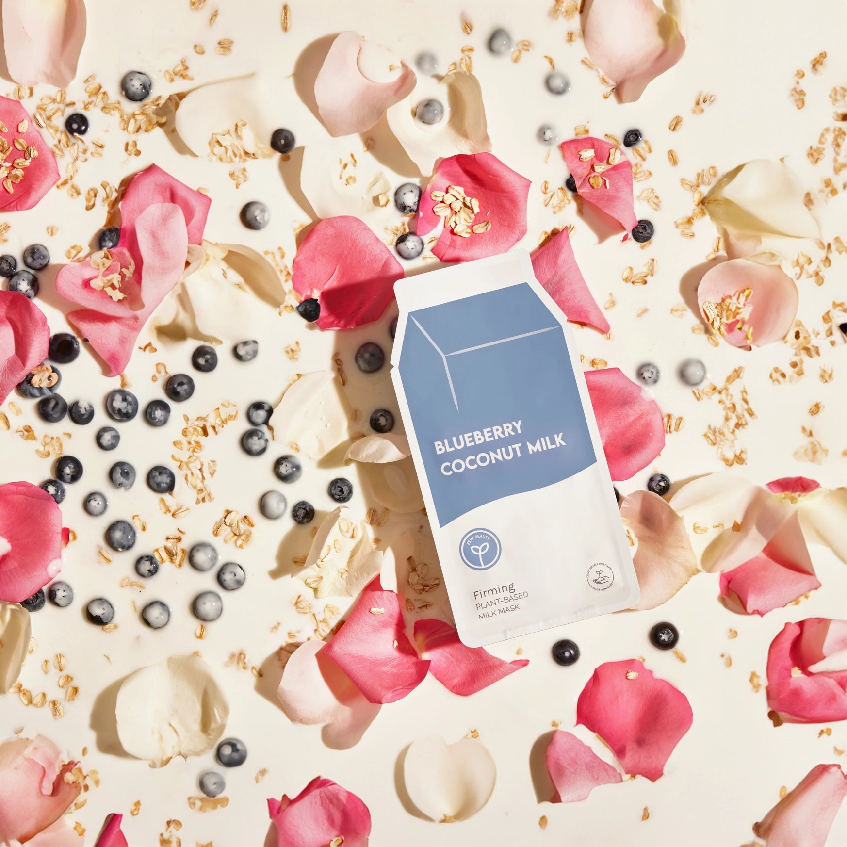 Blueberry Coconut Milk packaging surrounded by blueberries, flowers, and petals on a light background