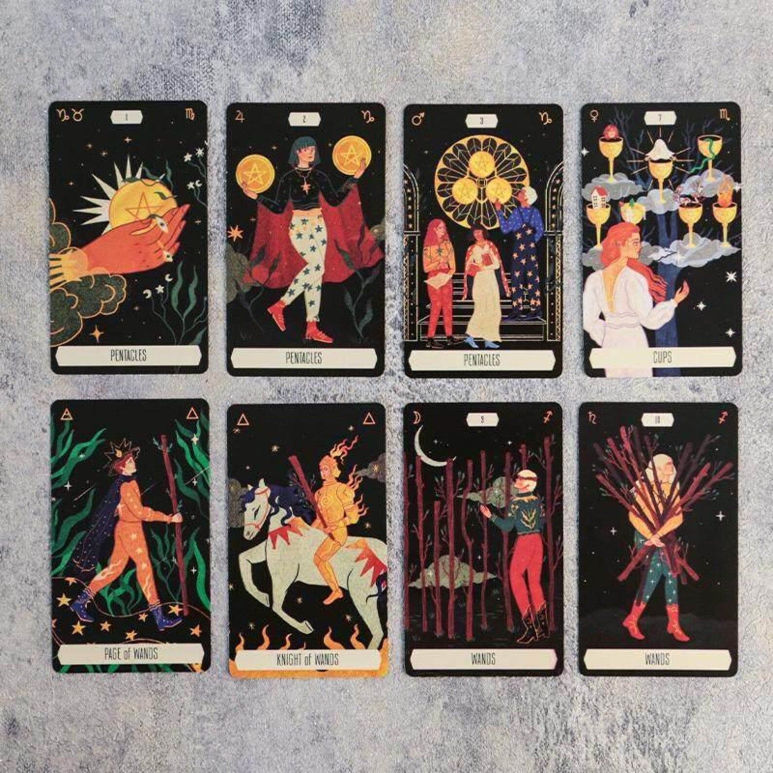 Eight tarot cards arranged in a 2x4 grid on a textured light gray background. The cards feature black backgrounds with colorful illustrations and titles including 'Fool', 'Temperance', 'Page of Wands', 'Knight of Wands', 'High Priest', and 'High Priestess'.