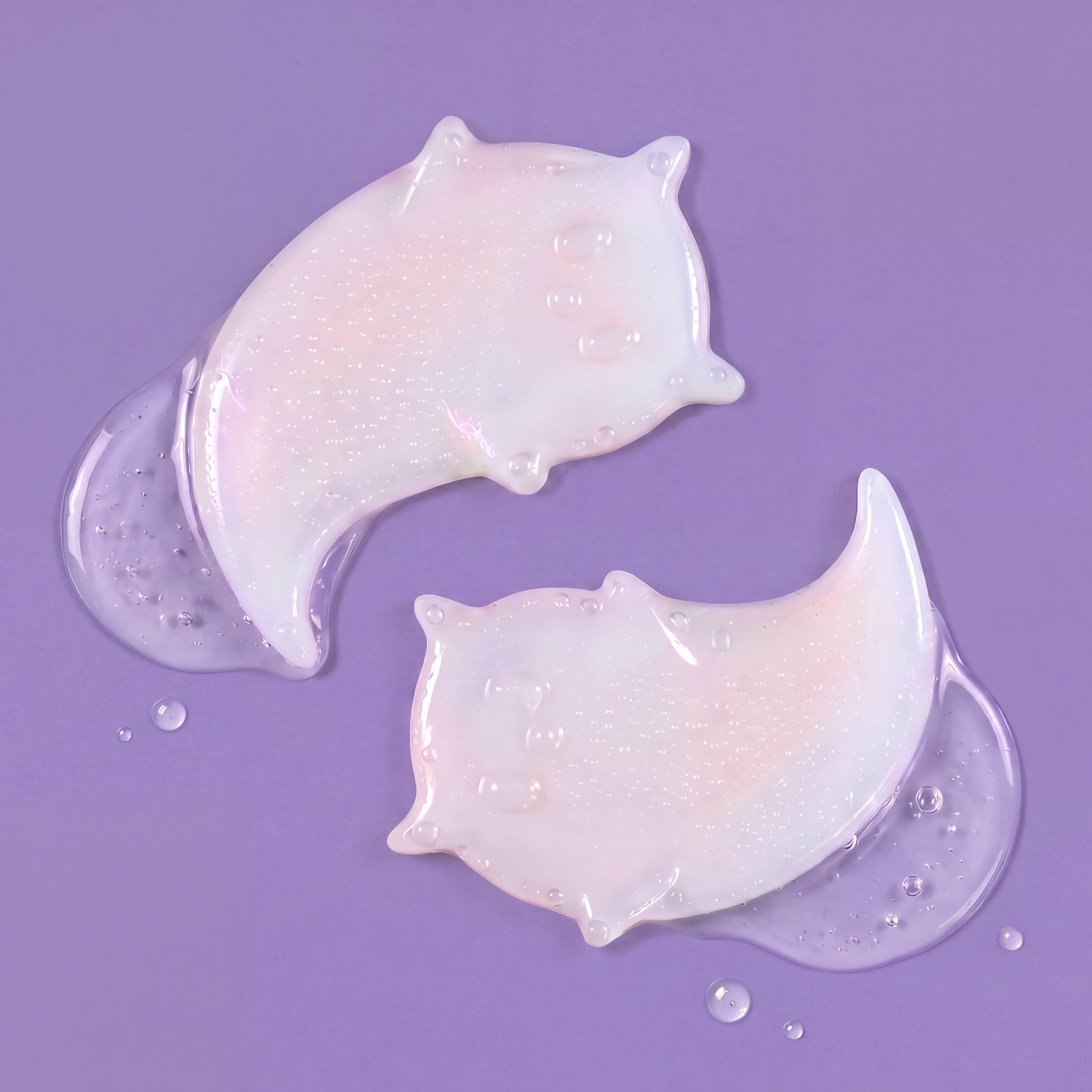 Two crescent moon-shaped adhesive bandages with a glossy, iridescent white finish and tiny glitter flecks, displayed on a solid purple background with a few clear liquid droplets.
