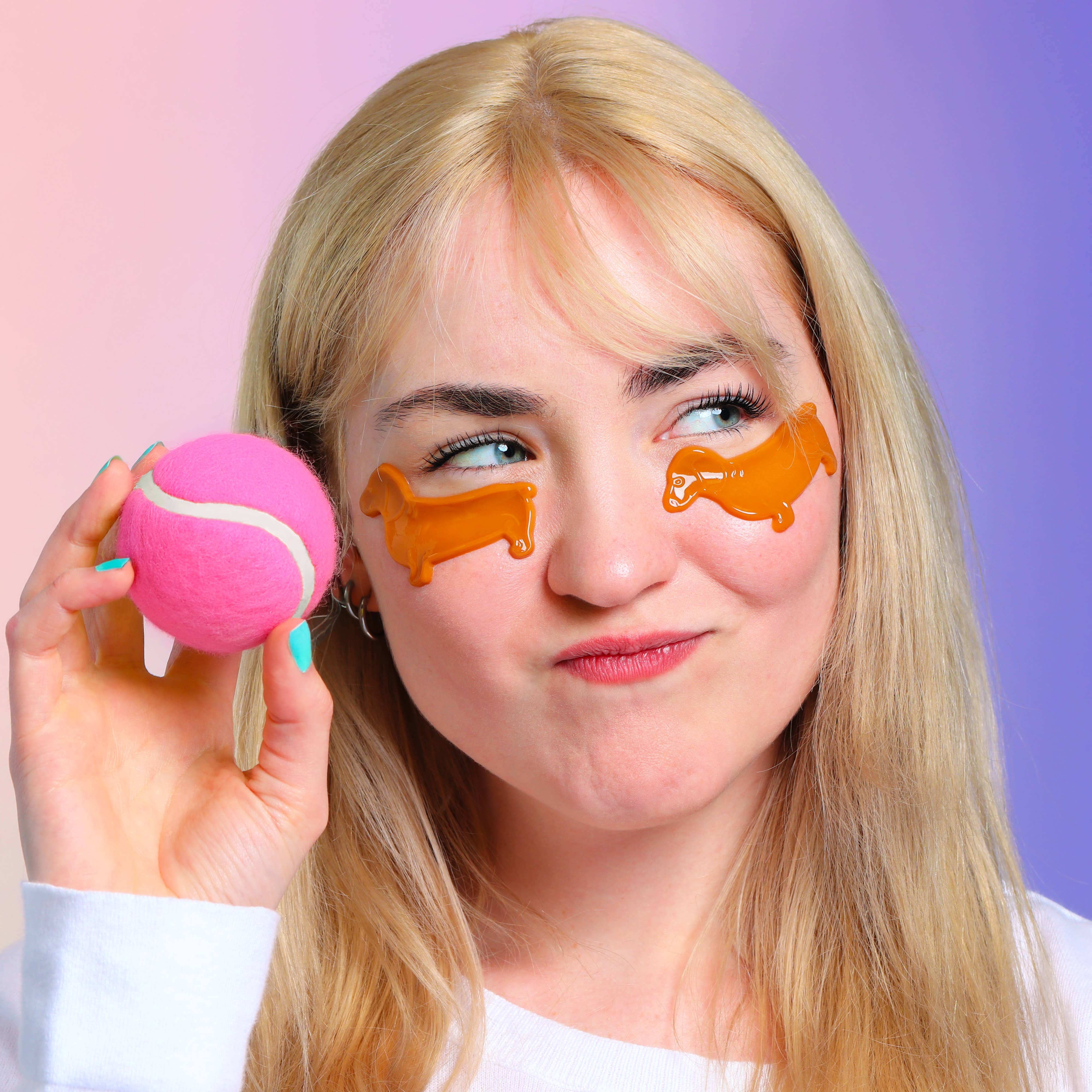 Woman with orange eye masks holding a pink tennis ball against a gradient background