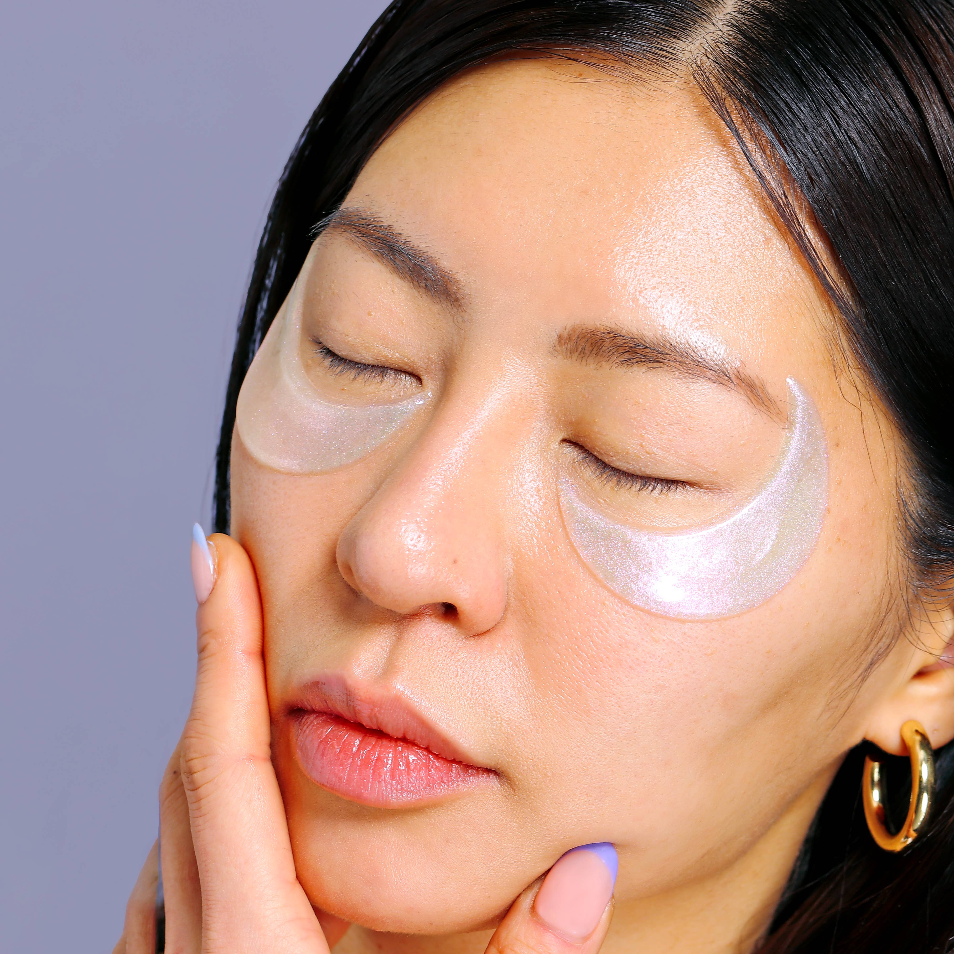 Woman wearing eye patches with a plain background