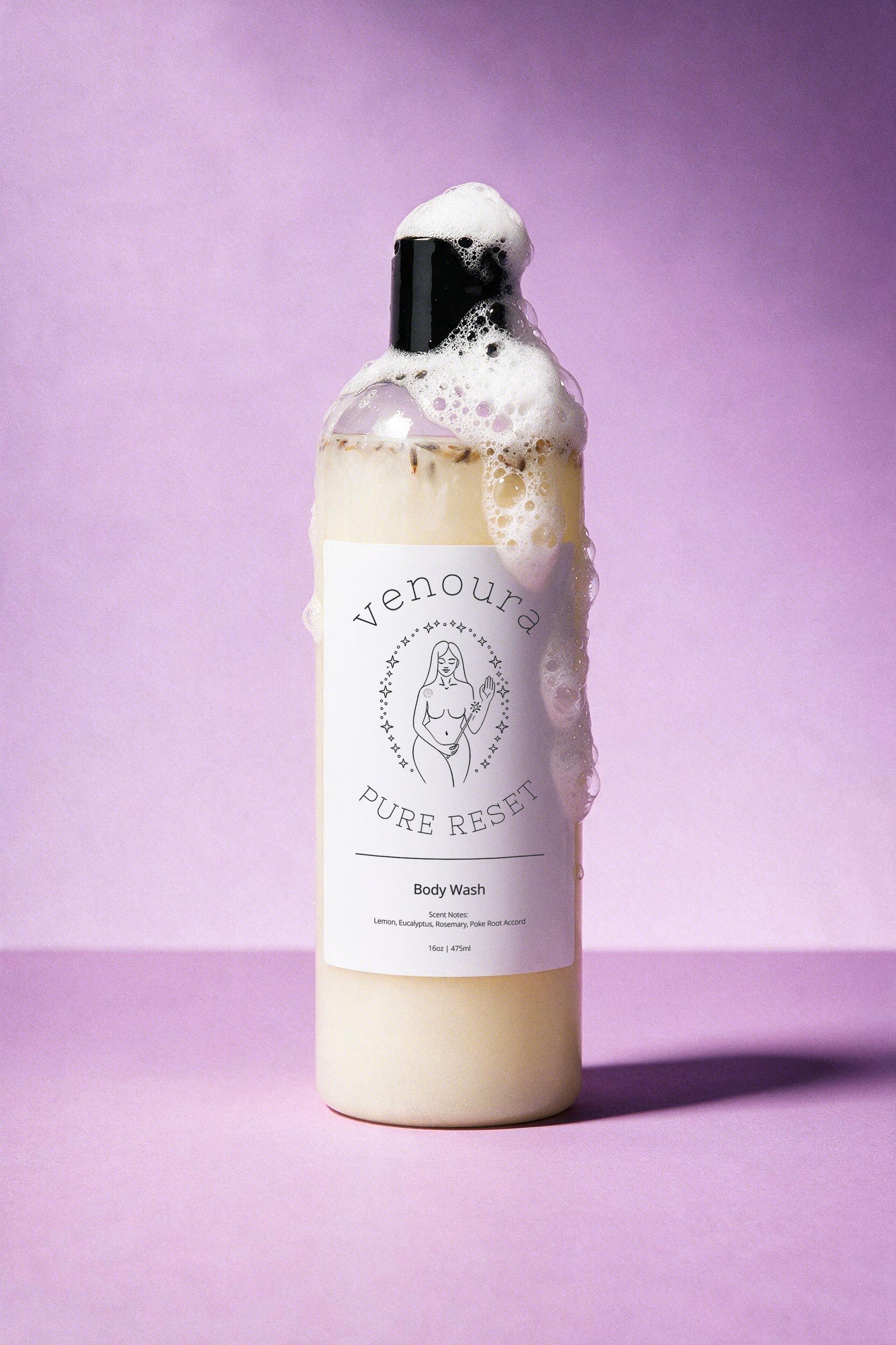A bottle of Venoura Pure Reset Body Wash filled with creamy off-white liquid, topped with overflowing white foam, set against a solid lavender-purple background.
